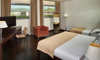 a hotel room with a bed , two chairs , a table , and a window overlooking the city at Hotel Cruise