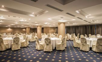 a large , empty banquet hall with white tables and chairs , blue carpeting , and gold stars on the floor at FlyOn Hotel & Conference Center