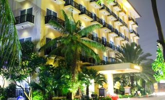 a modern hotel building with multiple balconies , surrounded by lush greenery and tropical plants , under the illumination of street lights at Narita Hotel Tangerang
