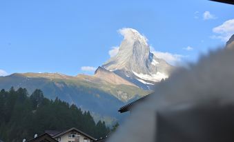 a snow - covered mountain with a large peak in the background , seen from the perspective of a window at Hotel Astoria