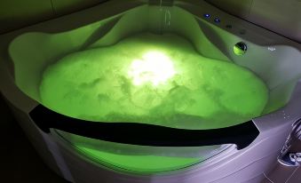 a large , illuminated bathtub filled with bubbles and green water is seen from above , illuminated by a warm light at Hotel River