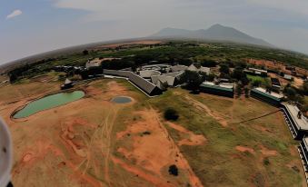 aerial view of a large building surrounded by grass and trees , with mountains in the background at VOI Wildlife Lodge