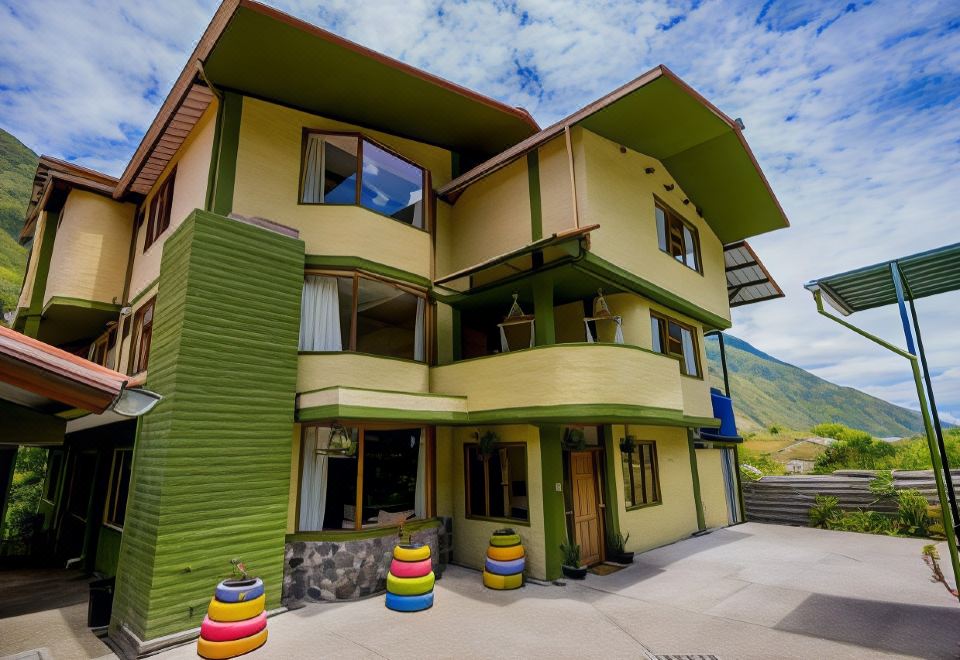 a green and yellow building with two balconies , surrounded by colorful planters on the front porch at La Casa Verde