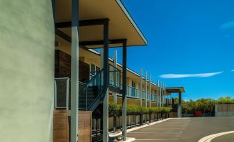 a building with a covered porch and outdoor seating area , under a clear blue sky at Brooklands of Mornington