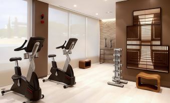 a modern home gym with various exercise equipment , including treadmills , stationary bikes , and weight machines at AC Hotel Cincinnati at Liberty Center