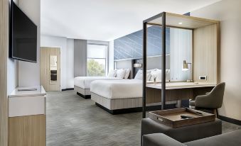 a modern hotel room with two beds , a couch , and a window , all decorated in white and gray colors at SpringHill Suites Dallas Rockwall