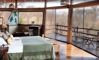 a bedroom with a large bed , wooden floor , and large windows overlooking a forest at Elewana Tarangire Treetops