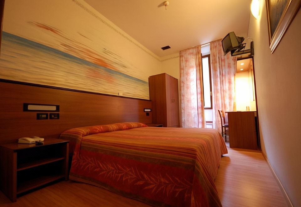 a hotel room with a large bed , wooden furniture , and a window with curtains , along with a tv on the wall at Hotel Leonardo