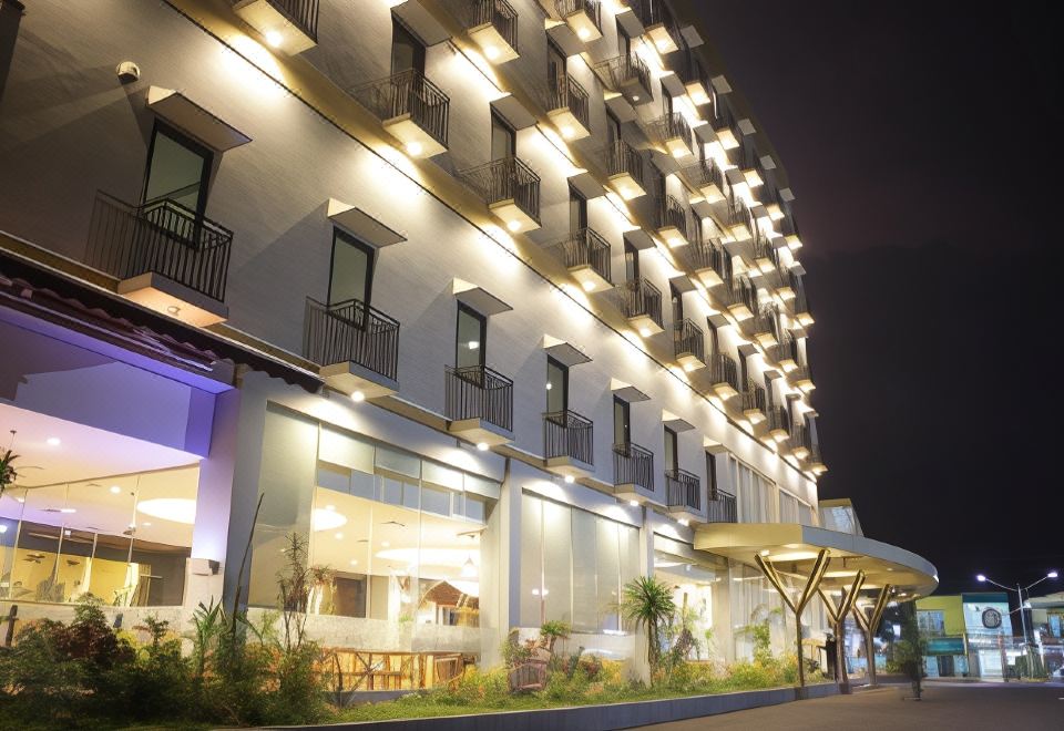 a modern building with multiple floors , balconies , and a central storefront at night , illuminated by lights at Hotel Horison Gkb Gresik