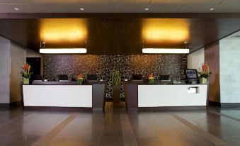 a modern office reception area with two white desks , each having a computer and a chair at DoubleTree by Hilton Montreal