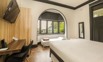 a modern hotel room with a large window , wooden floor , and two beds , one of which is made up with white sheets at Glenferrie Lodge