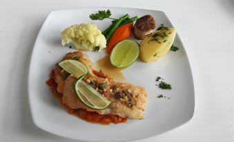 a white plate with a piece of chicken on top of a bed of rice , accompanied by various vegetables and sauces at Poonyamantra Resort