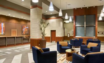 a large , well - lit lobby with blue couches , chairs , and a dining table , creating a comfortable atmosphere for meetings or socializing at Hilton Shreveport