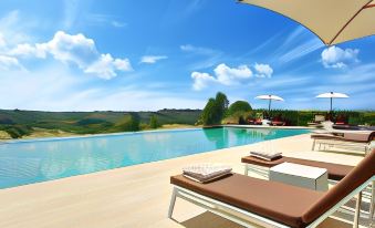 a luxurious outdoor pool area with sun loungers , umbrellas , and clear blue water under a sunny sky at Villa le Calvane