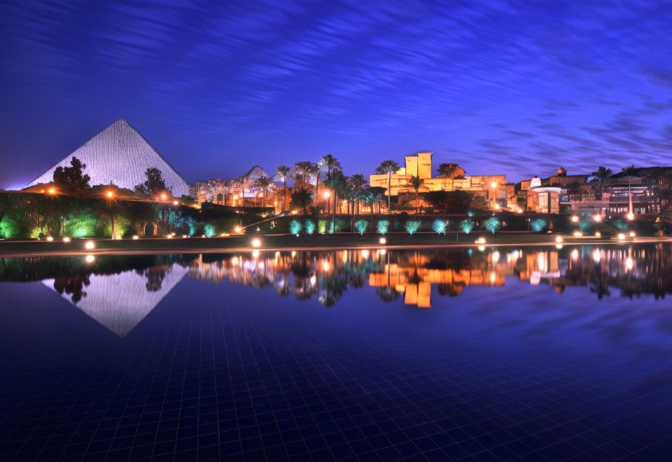 a city skyline at night , with buildings lit up and reflecting in a body of water at Marriott Mena House, Cairo