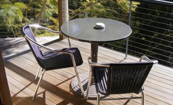 a wooden deck with two black chairs and a small round table , providing a cozy outdoor seating area at Tambaridge Bed & Breakfast