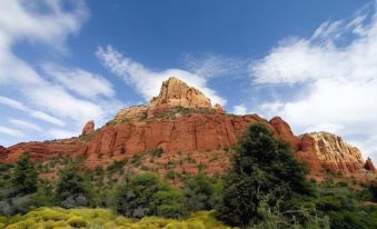 a red rock mountain with a tall peak is surrounded by green vegetation and a blue sky at Residence Inn Phoenix Goodyear