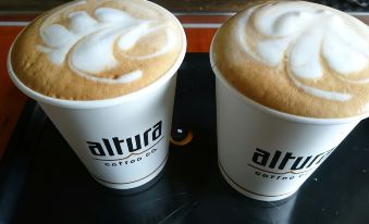 two cups of coffee with foam on top are sitting next to each other on a table at Anglers Lodge