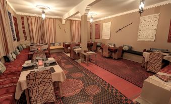 a room with tables and chairs , a rug on the floor , and hanging lights at Guest House Bagdad Café