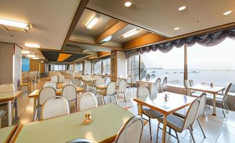 a large , empty dining room with numerous tables and chairs , providing a comfortable environment for guests to enjoy their meals at Hotel Urashima