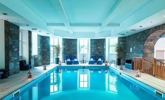 an indoor swimming pool surrounded by a lounge area , with several chairs placed around the pool at The Atholl Palace