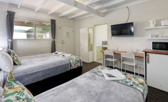 a room with two beds , a desk , and a television mounted on the wall at Oasis Motel