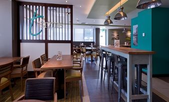 a modern restaurant with wooden tables and chairs , a bar , and a blue sign on the wall at Premier Inn Oban