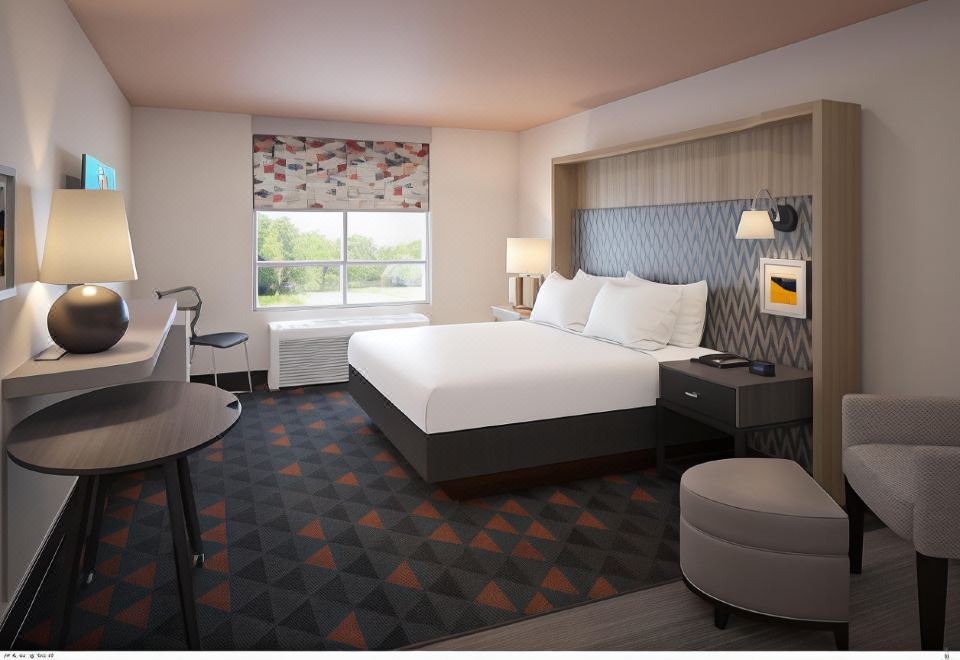 a hotel room with a large bed , two nightstands , and a desk , all arranged in a comfortable setting at Holiday Inn & Suites Hopkinsville - Convention Ctr