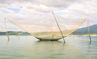 a large white sailboat floating on a body of water , with a net attached to it at Que Toi Village Resort Phu Yen