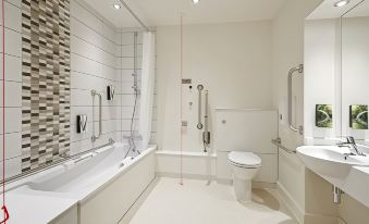a white bathroom with a shower , toilet , and bathtub , along with a red line drawn on the wall at Premier Inn Wadebridge