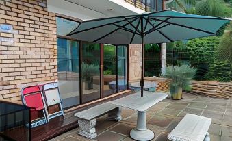 a patio area with a brick building , an umbrella , and a white bench under a blue umbrella at Hidden Inn
