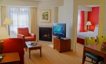 a living room with a fireplace , red couch , and a flat - screen tv . also a dining table in the room at Residence Inn Hartford Avon