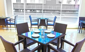 a glass dining table with four chairs surrounding it , and a row of chairs in the background at Putatan Platinum Hotel