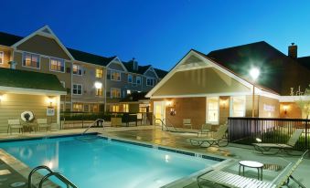 an outdoor swimming pool surrounded by a building , with people enjoying their time in the pool at Residence Inn Hartford Avon