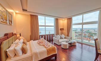 a spacious bedroom with a large bed , couch , and chairs near a large window overlooking the ocean at Lbn Asian Hotel