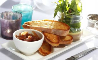 a white plate with slices of toast , a bowl of jam , and a small jar of sauce at Best Western Plus Oaklands Hotel