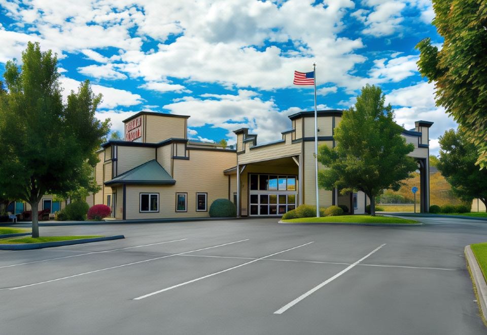 a large building with a parking lot in front of it , and an american flag on the flagpole at Oxford Suites Pendleton