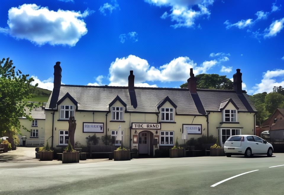 "a large , yellow building with two - story roofs and the words "" the old stables "" written on it" at The Hand at Llanarmon