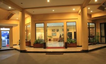 a well - lit entrance to a building with large glass doors and potted plants on either side at Hotel Grand Papua Fakfak