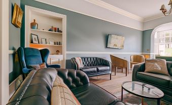 a living room with a blue wall , black leather furniture , and a flat - screen tv mounted on the wall at Oakhill