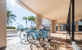 a row of blue bicycles parked on a sidewalk , with a building in the background at Goldsborough Place Apartments