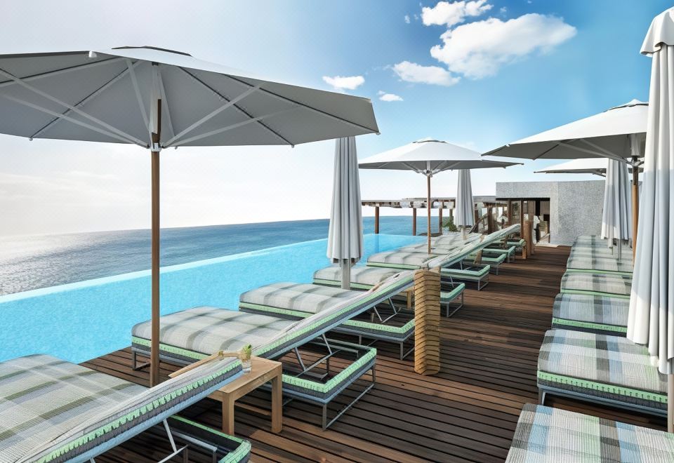 a wooden deck with several lounge chairs and umbrellas , providing a relaxing atmosphere near the ocean at Ocean V Hotel