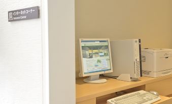 a computer monitor and keyboard are on a desk in an office setting , with a computer on the wall nearby at The Orion Hotel Motobu Resort & Spa