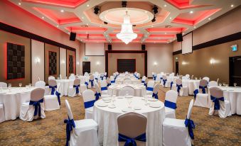 a large banquet hall with multiple tables set for a formal event , featuring white tablecloths and blue napkins at Ramada by Wyndham Jacksons Point