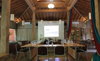 a large conference room with wooden walls , a projector screen , and tables set up for a meeting at Rumah Batu Boutique Hotel