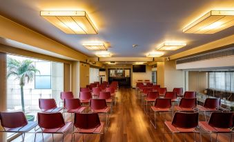 a large conference room with rows of red chairs arranged in a semicircle , and a projector on the wall at Nafs Hotel