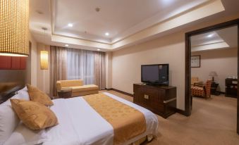 a large bed with a gold blanket is in a room with a television and window at Royal Hotel