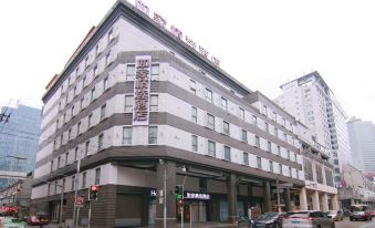 There is a large building at an intersection with cars parked in front on the street outside at Home Inn Plus (Shanghai Bund Jinling East Road store)