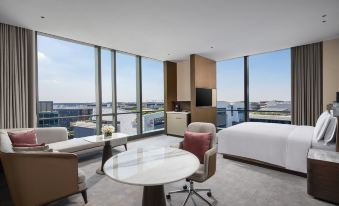 The room is furnished like an apartment, featuring large windows, a bed, and a table in the center at Crowne Plaza Shanghai Hongqiao