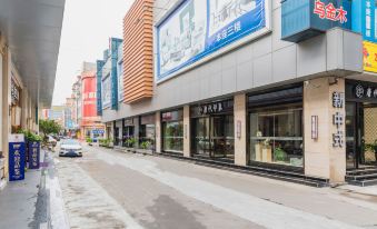 There is a street with numerous stores on both sides, with an empty sidewalk in the middle at Aishan Hotel (Foshan Shunde Lecong Furniture City store)